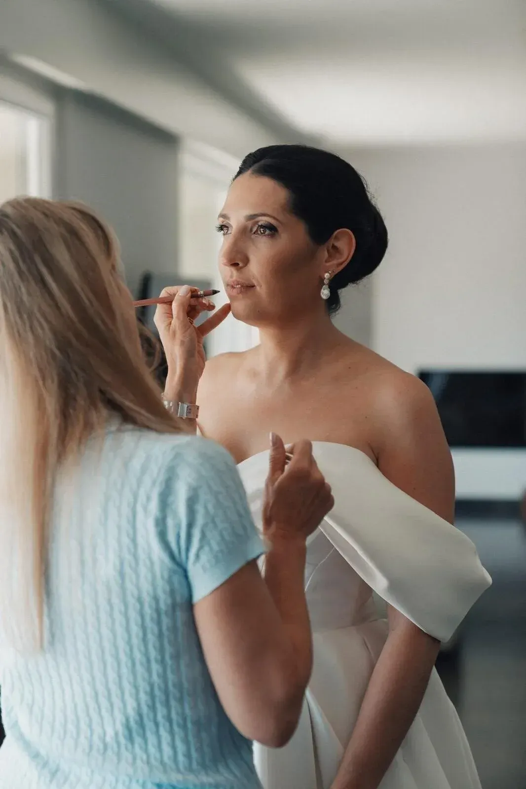 Mariée en robe blanche pendant la séance de maquillage