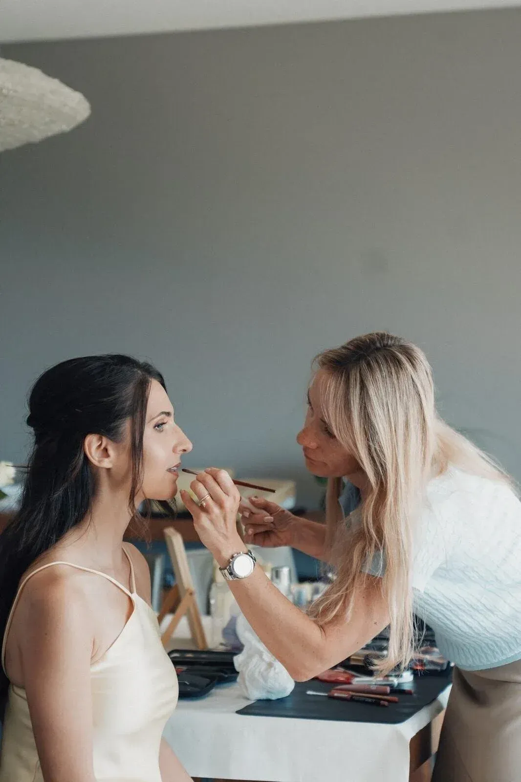Femme en robe crème se faisant maquiller à l'intérieur