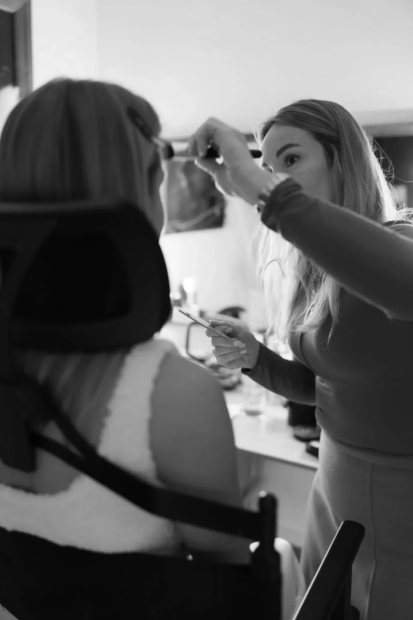 Maquilleuse maquillant une femme aux cheveux longs dans un salon ou un studio de maquillage.